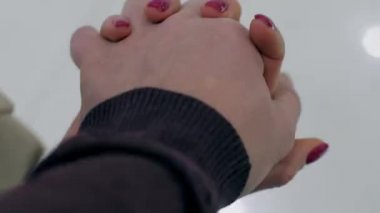 Kırmızı manikürlü genç bir kadın, erkek arkadaşının elini sıkıca tut.