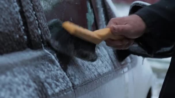Persoana curăță fereastra vehiculului electric de gheață umedă — Videoclip de stoc