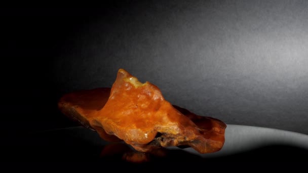Yellow amber stone of strange form lies on glass support — Stock Video