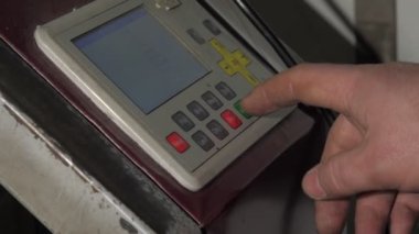 Sanatçı, çalışma tezgahı denetleyicisindeki yeşil başlatma düğmesine basıyor
