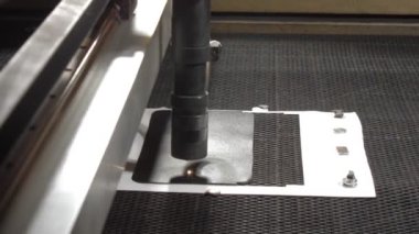 Lazer kesici, deri kredi kartı kılıfında daireler çiziyor.