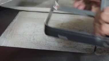 Yaşlı kadın elleri siyah deri kumaşı hareket ettir ve metal bıçağı tak.