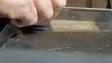 Terzi, tezgah desteğinde küçük deri daireler sayar.