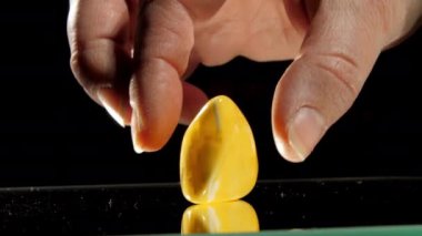 İnsan eli, aynaya sarı Matt Amber taşı koyar.