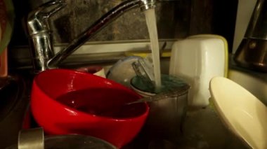 Kişi çatal bıçak takımını süngerle yıkayıp konteynıra koyar.