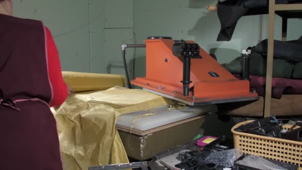 Old tailor in apron fixes large yellow metal roll on press — Stock Video