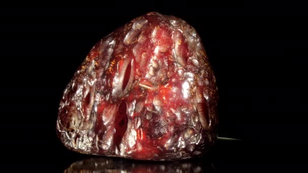 Дорогоцінний червоний бурштиновий камінь дивної форми лежить крупним планом — стокове відео