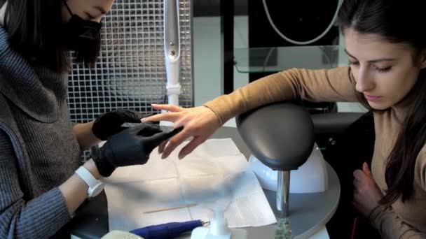 Манікюрник у масці для обличчя та рукавичках створює форму нігтів — стокове відео