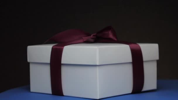 Різдвяна коробка зі стрічкою під барвистими блимаючими вогнями — стокове відео