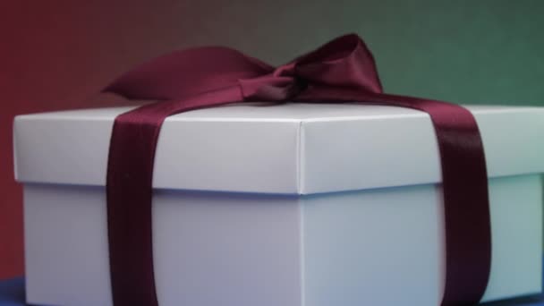 Caja de Navidad con cinta bajo luces intermitentes de colores — Vídeo de stock