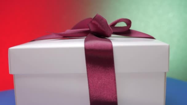 Caja festiva blanca con cinta púrpura y lazo en la parte superior gira — Vídeos de Stock