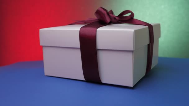 Pudełko świąteczne ze wstążką pod kolorowymi lampkami błyskowymi — Wideo stockowe