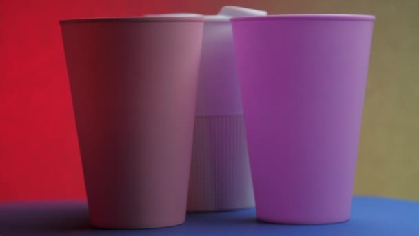 Les tasses à boisson pourpres blanches et roses tournent sur la table bleue — Video