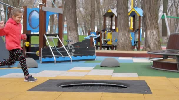 Verblüffte junge Frau springt auf schwarzem Trampolin auf Spielplatz — Stockvideo