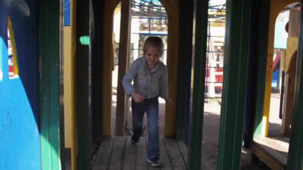 Criança encantada com cabelos claros corre em labirinto artificial — Vídeo de Stock