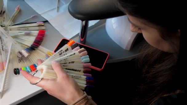 Morena de pelo largo mira ejemplos de colores de manicura — Vídeos de Stock