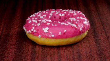 Üzerine beyaz şeker serpiştirilmiş pembe şekerli lezzetli donut.
