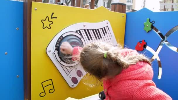 Interested schoolgirl rotates piano and presses buttons — Stock Video