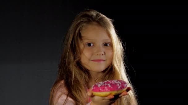 Hosszú laza hajú szőke általános iskolás lány harap fánk — Stock videók