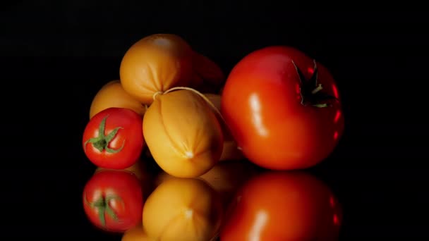 Los tomates cherry y los pandilleros marrones yacen sobre una mesa de vidrio negro — Vídeo de stock