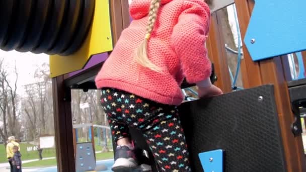 Zabawna dziewczyna w legginsach i kurtce wspina się na atrakcję — Wideo stockowe