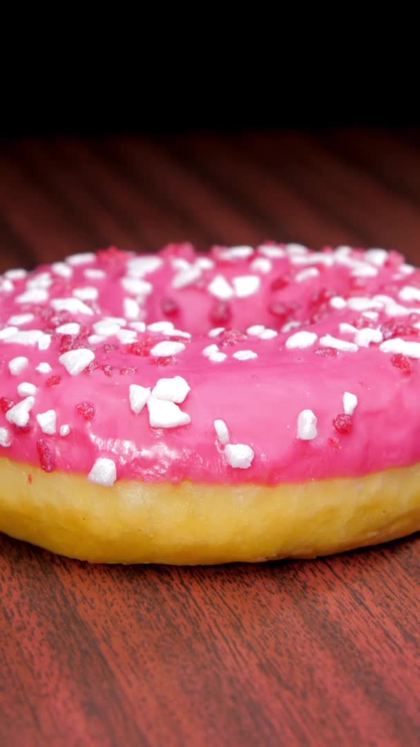 Lekkere donut met gekleurde room op bruine houten tafel — Stockvideo