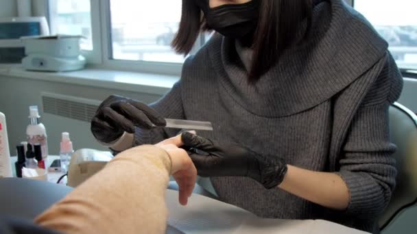 Geschoolde schoonheidsspecialiste in handschoenen maakt manicure op vingernagels — Stockvideo