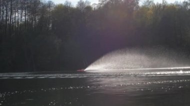 Kırmızı radyo kontrollü tekne sakin göl suyu boyunca yelken açıyor.