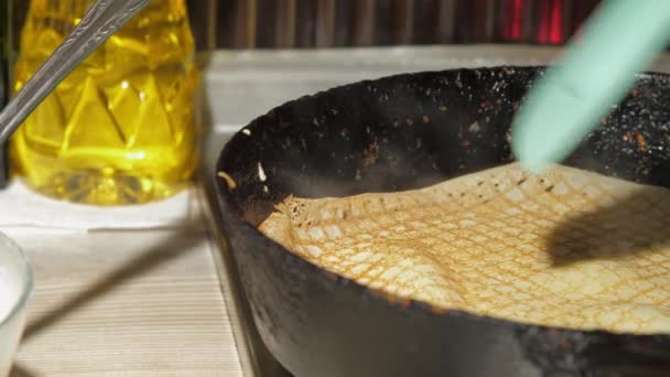 人们把热黄色的煎饼固定在旧的黑油锅上 — 图库视频影像