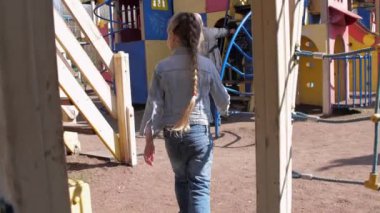 Kot pantolon ve ceket giyen sarışın liseli kız koşuyor.