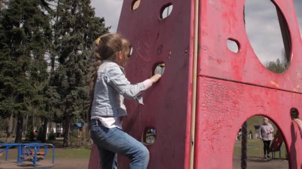 Блондинка младшей школы с косой взбирается на деревянную стену — стоковое видео