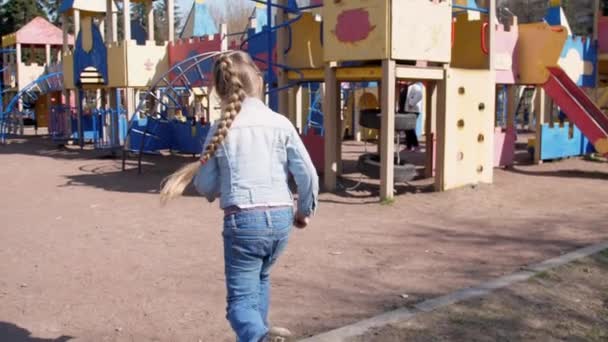 Блондинка младшей школы бежит вдоль красного аттракциона в замке — стоковое видео