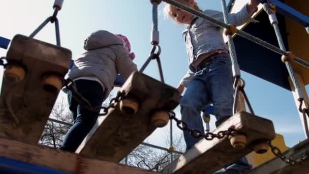 Niña pequeña con pelo en trenza camina a lo largo del puente colgante — Vídeos de Stock