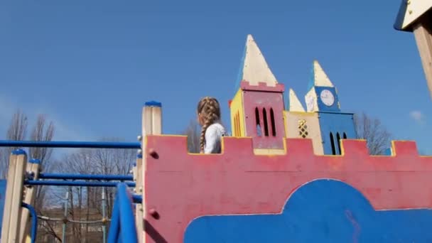 Cuidado colegiala rubia camina a lo largo del parque infantil castillo — Vídeo de stock