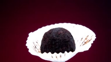 Beyaz kağıtta el yapımı siyah çikolata şekeri dönüyor.