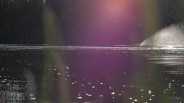 Uzaktan kumandalı tekne göl boyunca yansımalarla yol alır.