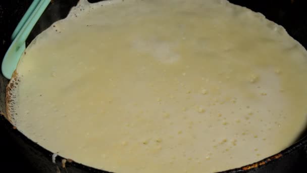 Κίτρινη λευκή ζύμη τηγανίτες σε μαύρο τηγάνι επιφάνεια — Αρχείο Βίντεο