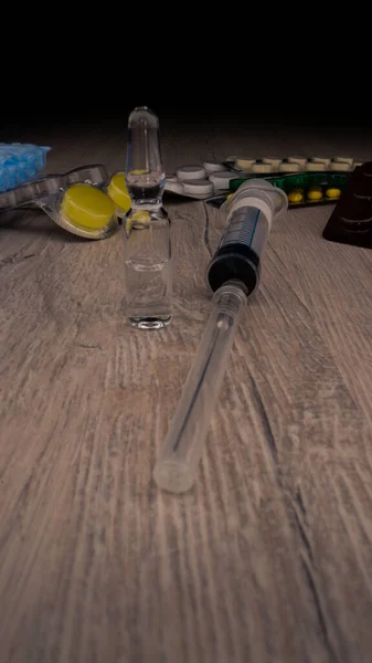 Vial transparente con vacunas sobre la mesa frente a las píldoras —  Fotos de Stock
