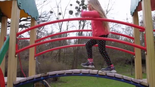 Jong schoolmeisje met lang mooi haar klimt omhoog attractie — Stockvideo