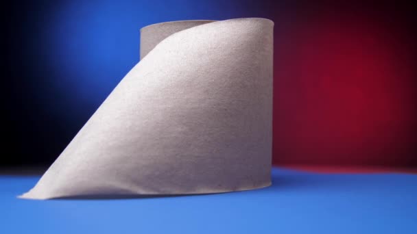 Grå rulle toalettpapper på bordet mot blått och rött — Stockvideo