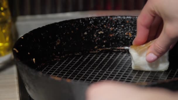 Домогосподарка протирає чорну сковороду з білим жирним шматочком — стокове відео