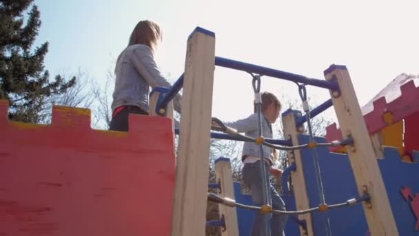 Moeder houdt junior schoolmeisje wandelen langs speeltuin — Stockvideo