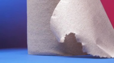 Grey roll of toilet paper with rumpled edge rotates