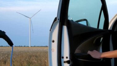 Rüzgar türbini elektrik yüklüyor Tesla hanım ve araba istasyonda.