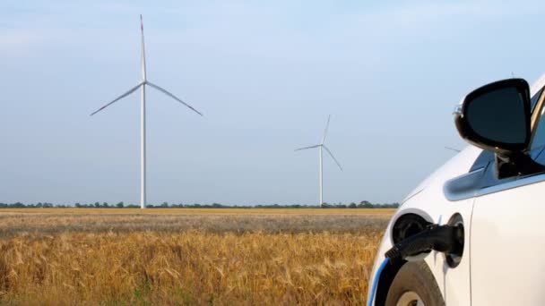 Windturbine laadt elektrische auto door energie in tarweveld — Stockvideo