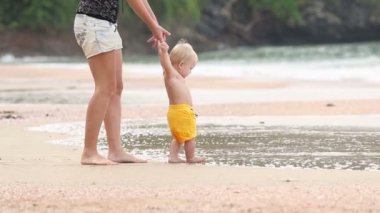 Çocuk tanıtıcıyla annesiyle kumsalda yürür