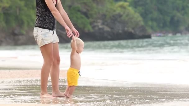 Παιδάκι περπατά από λαβή με μητέρα στην παραλία — Αρχείο Βίντεο