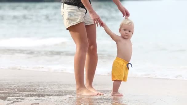 dítě chodí rukojeť s matkou na pláži