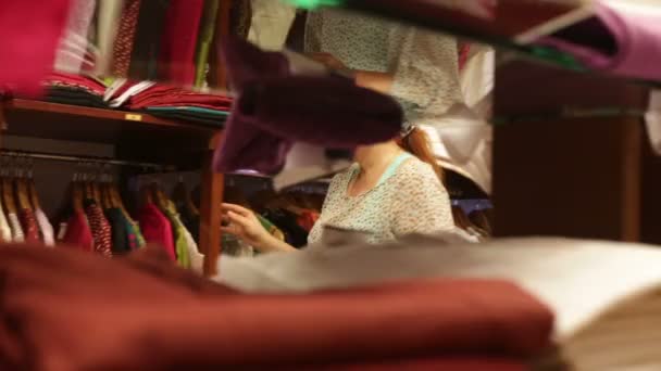 Vrouw kiest kleren in een winkel — Stok video