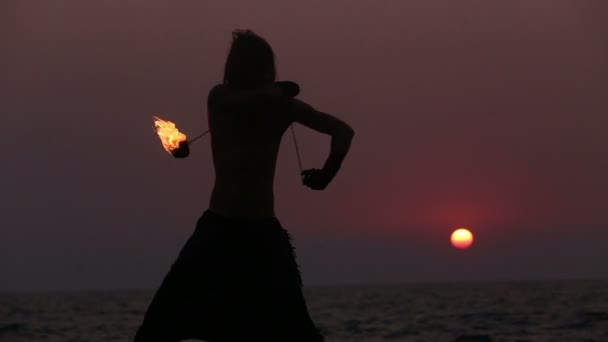 Male Artist of the spins fire poi on a rock — Stock Video